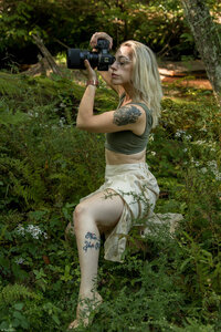 woman in woods  holding canon camera