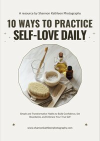 Flat lay photo with a cozy beige notebook, pen, warm coffee mug, and pampas grass arranged on a soft fabric background, representing a calming self-love journaling scene.