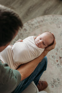 Baby girl in dad's lap during a newborn photoshoot in Itasca, IL