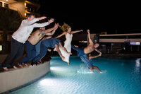 bride and groom jumping into pool