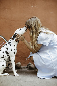 adult-black-and-white-dalmatian-licking-face-of-woman-1389994