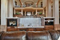 A wide view of the interior of a two story home with a wine bar, balcony, and arching staircases.