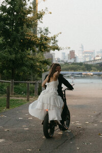 Bride riding on the back of the grooms motocycle as they wave goodbye to leave the reception in Brooklyn, NYC.