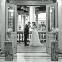 Groom kisses bride hand , this photo is in black and white.