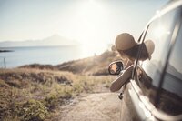 photo d'une femme sortant la tête de la fenêtre d'une voiture, et regardant la mer