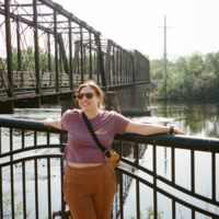 Rachel leaning against a bridge, smiling