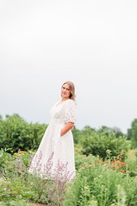 a girl in a cream dress posing in a flower field