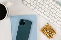 A cell phone and notebook sitting on a computer desk