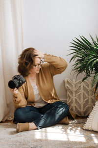 A photographer holds her camera while sitting on the floor