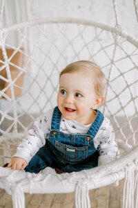 little boy smiling in in a rope chair