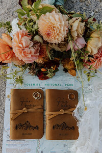 flatlay of vow books, yosemite map, rings, and floral bouquet