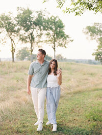 Portrait of couple with their arms around each other standing in a grassy field