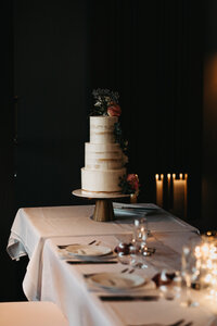 three tiered wedding cake with topper at wedding reception