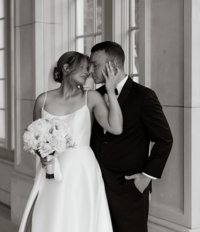 A romantic black and white wedding portrait at The Olana in Hickory Creek, Texas, featuring a joyful bride and groom sharing an intimate moment in a grand architectural setting.
