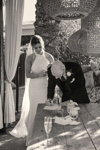 Black and white photo of Bride and groom signing marriage papers after  Arizona outdoor ceremony.
