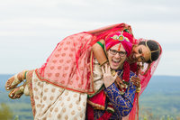 Groom holding bride over his shoulders during an Indian fusion wedding, showcasing vibrant wedding photography styles.