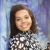 Senior girl leans against mural