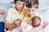 Two brothers holding their newborn sister during a Haymarket photo session.