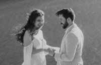 A bride and groom exchange heartfelt vows with wind in their hair, smiling at each other during their Glacier National Park elopement, captured by Sydney Breann Photography.