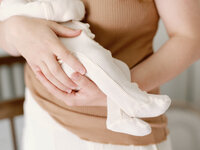 Baby in a jumper being held by their mother