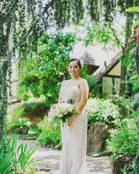 Portrait of Bride standing holding her bouquet smiling at the camera