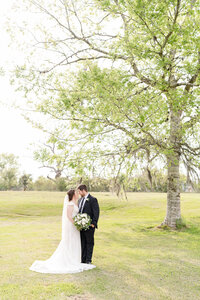 Bride and Groom forehead to forehead while holding bouquet under tree at Cross Key Acres