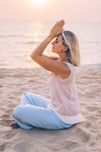 woman with blond hair meditating on beach