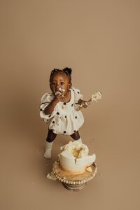 girl eating cake during first birthday pictures in tampa