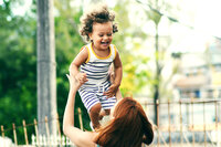 Mom throwing laughing baby in air