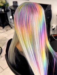 Image of client with hair that has been dyed a white blonde with a light, pastel, vivid, rainbow pattern.