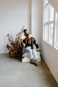 mixed race couple looking out window in studio