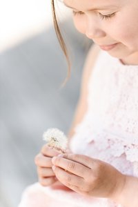 Hender til ei jente som holder en blomst