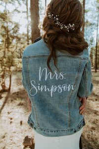 Bride wears a jean jacket with her new last name