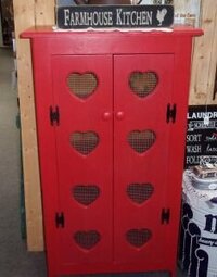 tall pie safe painted red with heart cutouts in the doors