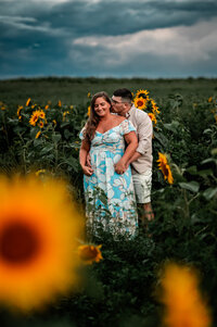 couple loving on eachother in a sunflower field in upstate ny