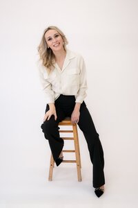 Arizona wedding photographer Joy sitting on a stool in a photography studio