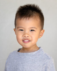 Asian boy in gray shirt smiling for preschool photo with beige white backdrop Bay Area School Photography Ellobelle Photography 
