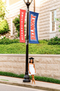 Senior girl in white wearing her cap and leaning against a light post