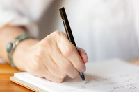 pen in hand writing on paper