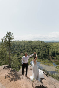 A newlywed couple dancing on a hiking trail 