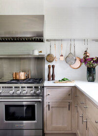 Boston kitchen designer creates a Westwood home with natural white oak cabinets, white counters, a stainless backsplash, and counter-to-ceiling subway tile.