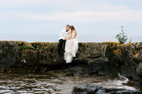 Bride and groom sitting on the rock with heads together in the moment of lake Superior on the North Shore wedding in Minnesota. 