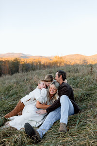 Family photo with two boys tackling their mom and everybody laughing.