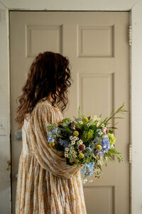 Pittsburgh wedding florist Heavenly Blooms looking to the side while holding a large floral arrangement