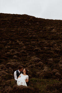 bride and groom sitting in the grass