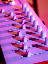 High-contrast close-up of keyboard under pink and purple studio lights – brand detail shot for music artists by Mewphotovideo