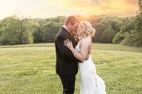 bride and groom forehead to forehead with sunset and fields