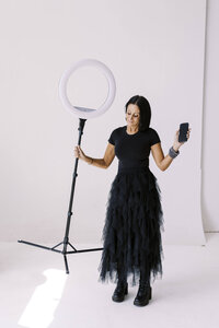 Tarah wearing a black tool dress holding stage light