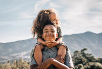 Brother giving younger sister a piggyback ride for their family portrait session with Chandra Wicke Photography