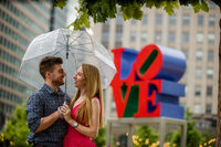 An engaged couple celebrating their love at the famous LOVE Statue in Philadelphia, blending romance and city vibes.